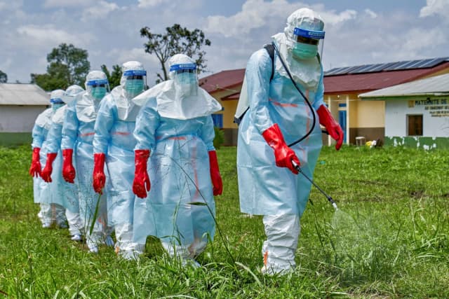 Trabajadores de la Cruz Roja caminan en formación mientras desinfectan el hospital general de Rwampara antes de manipular el cuerpo de una persona que murió de ébola, mientras las agencias de ayuda intensifican los esfuerzos para contener un nuevo brote de ébola que involucra la cepa Bundibugyo, en Rwampara, cerca de Bunia, provincia de Ituri, Congo, el 21 de mayo de 2026. (Gradel Muyisa Mumbere/Reuters).
