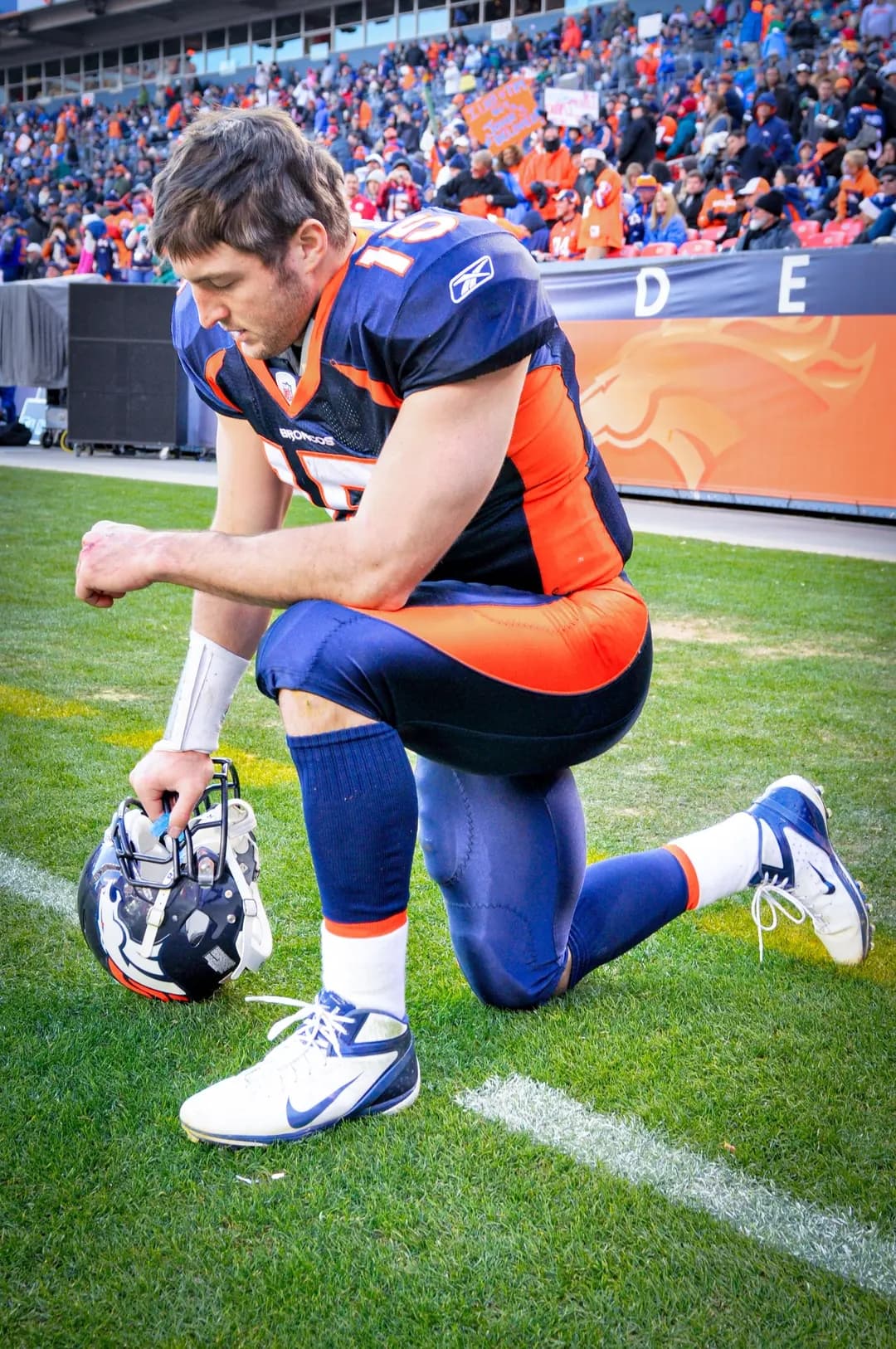 Tim Tebow, entonces mariscal de campo de los Broncos de Denver, realiza su característica pose “Tebowing” antes de un partido contra los Jefes de Kansas City en el Empower Field at Mile High de Denver el 1 de enero de 2012. La “Ley Tim Tebow”, que permite a los estudiantes educados en casa participar en actividades deportivas de las escuelas públicas, lleva el nombre del mariscal de campo de la NFL, quien también recibió educación en casa. (Ed Clemente Photography/CC BY-SA 3.0)