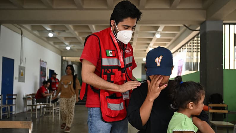 <em>Una mujer con un niño recibe una revisión médica en el hospital temporal de Medical Impact, instalado en una escuela de San Martín, en el municipio Libertador de Caracas, el 10 de julio de 2026, tras los terremotos del 24 de junio.  (Raul ARBOLEDA / AFP vía Getty Images)</em>