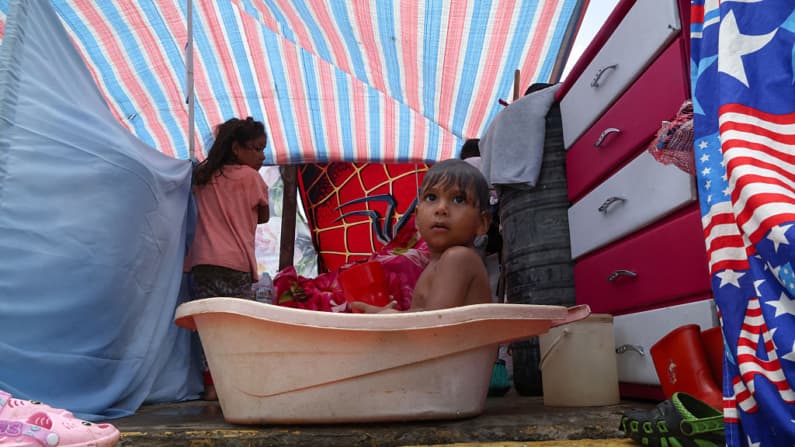 <em>Un niño desplazado de un edificio dañado se baña en un refugio instalado en la calle, tras el doble terremoto que sacudió Venezuela y otras regiones del Caribe, en una imagen del 29 de junio de 2026 en Caracas, Venezuela. (Edilzon Gamez/Getty Images)</em>