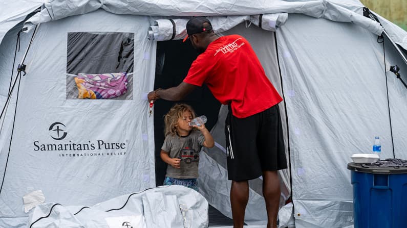 <em>Un niño bebe agua en la entrada de una carpa en el estadio de béisbol César Nieves en el barrio La Angustia de Catia La Mar, en La Guaira, Venezuela, el 3 de julio de 2026, donde se refugiaron personas desplazadas. (Miguel MEDINA/AFP vía Getty Images)</em>