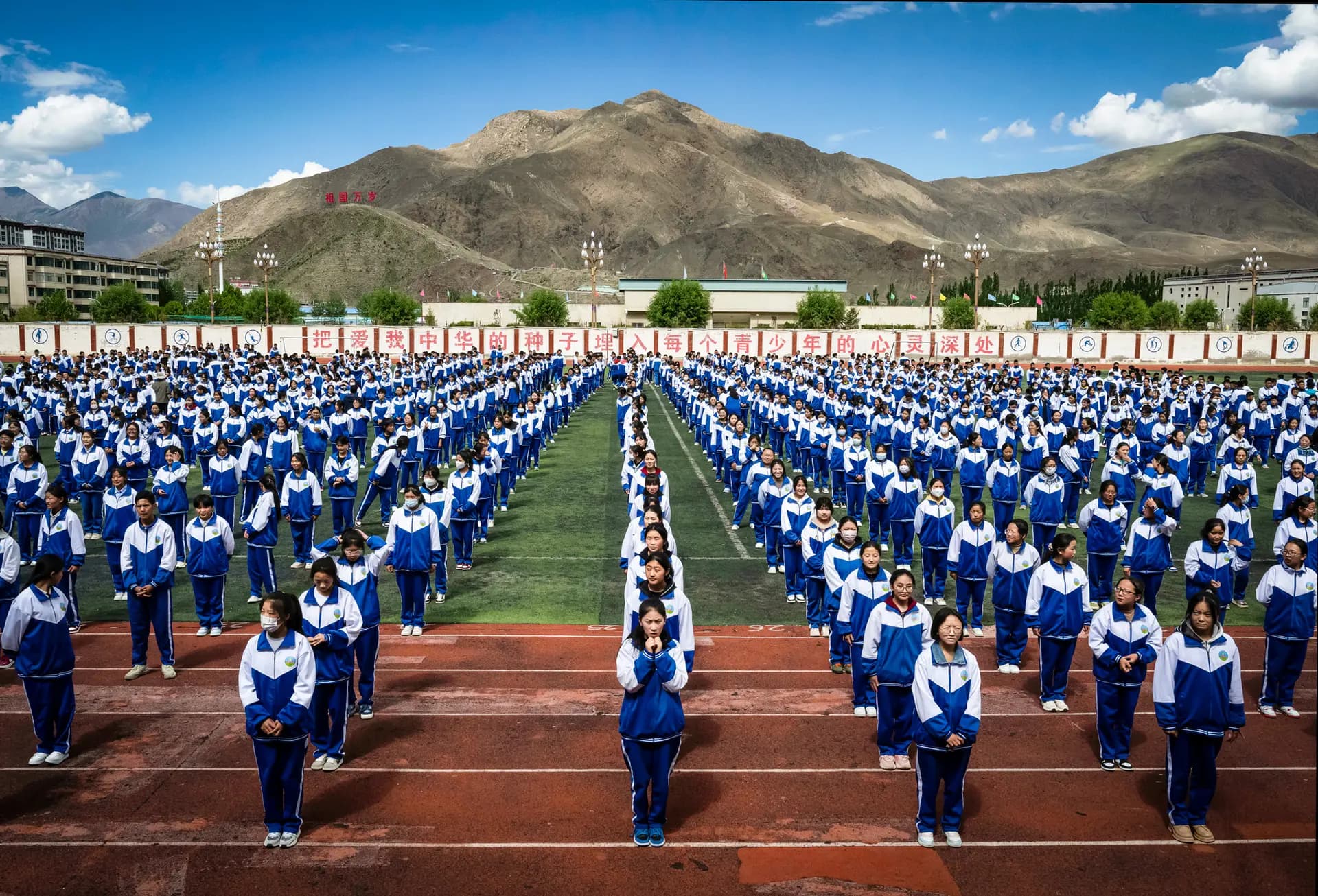 Estudiantes tibetanos de la Segunda Escuela Secundaria Superior hacen fila durante una visita organizada por el gobierno en Shannan, Tíbet, China, el 18 de junio de 2023. La politóloga June Teufel Dreyer señaló que muchos de los métodos de vigilancia que se utilizan actualmente en toda China se probaron primero en Xinjiang y en el Tíbet. (Kevin Frayer/Getty Images).