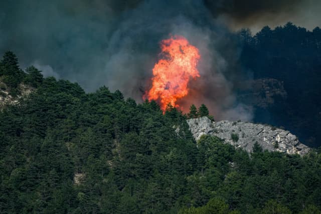Humo y llamas procedentes de un incendio que quema pinos y otros árboles sobre el pueblo de Barsac, cerca de Die, en el departamento de Drôme, al sureste de Francia, el 7 de julio de 2026. (Foto de Nicolas Guyonnet / Hans Lucas / AFP vía Getty Images).