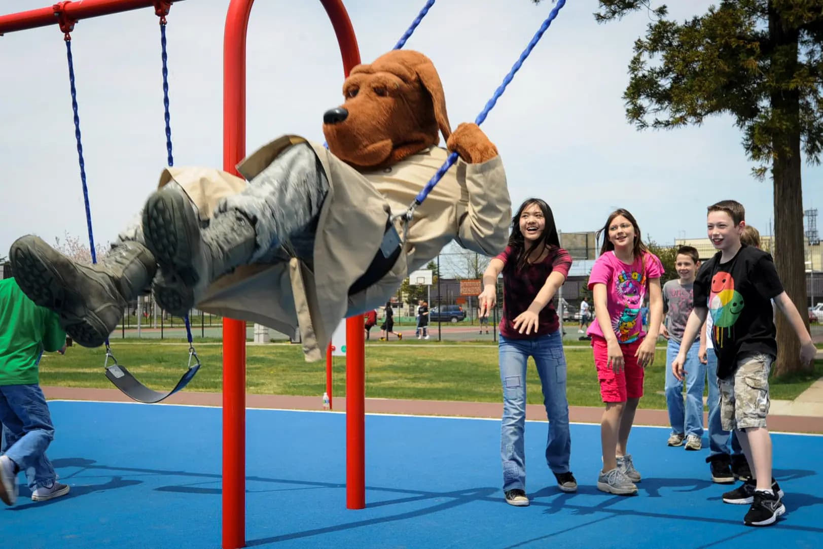 En apoyo a la Semana de la Policía, los alumnos de la Escuela Primaria Sollars empujan a McGruff, el perro contra el crimen, en los columpios durante el recreo en la Base Aérea de Misawa, Japón, el 14 de mayo de 2012. McGruff les recuerda a los niños que se mantengan alejados de las drogas y que eviten el acoso escolar diciéndoles: "McGruff los está vigilando". (Aviador Kenna Jackson/35.ª Ala de Caza de la Fuerza Aérea de EE. UU. vía DVIDS).