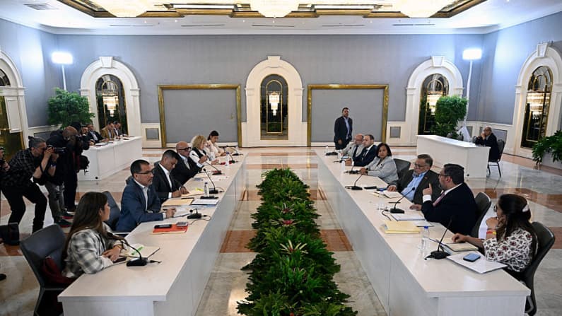 <em>Miembros del gobierno (izq.) y de la oposición asisten a una reunión del proceso de diálogo político entre representantes de ambas partes en el Centro de Convenciones de La Carlota, en Caracas, el 7 de agosto de 2026. El gobierno interino de Venezuela y los delegados de la oposición celebraron una primera reunión el 6 de agosto en el marco de un proceso de diálogo auspiciado por Estados Unidos, que muchos esperan conduzca a una transición política y a la celebración de elecciones. (Federico PARRA / AFP vía Getty Images))</em>