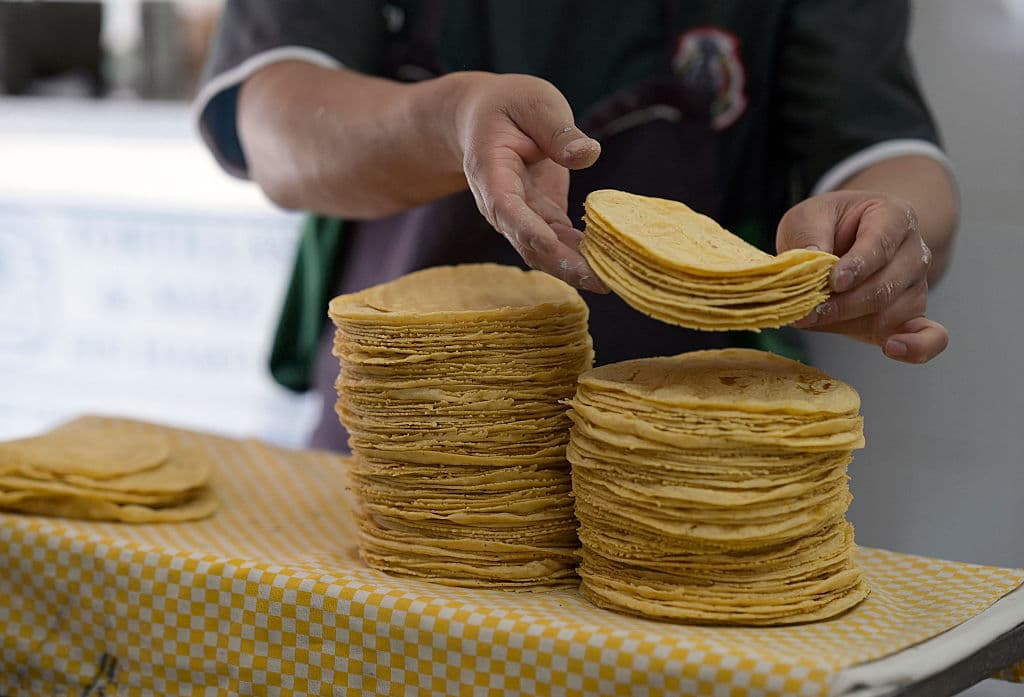 <em>Un trabajador acomoda tortillas en una tortillería en la Ciudad de México el 21 de septiembre de 2022. Según consultores agrícolas, el precio de las tortillas de maíz —un alimento básico en la dieta mexicana— aumentó casi un 70 % del inicio de la pandemia a septiembre del 2022. (ALFREDO ESTRELLA/AFP vía Getty Images)</em>