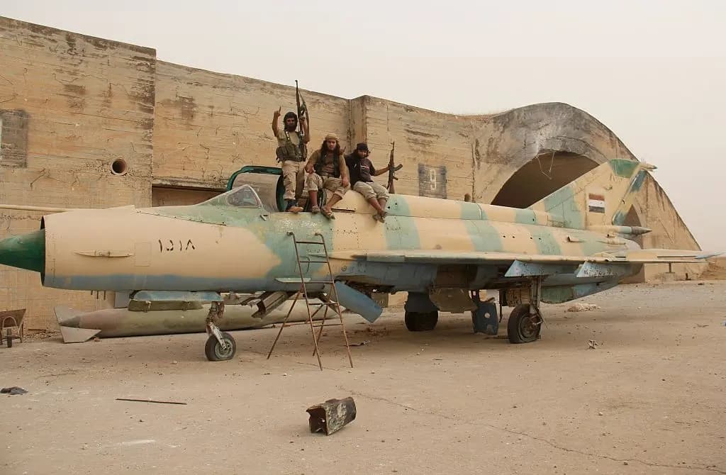 Miembros de la filial siria de Al-Qaeda, el Frente Al-Nusra, y sus aliados se sientan sobre un antiguo avión de combate MiG-21 del ejército sirio tras tomar la base aérea de Abu al-Duhur, en el noroeste de la provincia de Idlib, el 9 de septiembre de 2015. (Foto de Omar Haj Kadour/AFP)