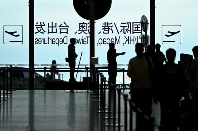 Un guardia de seguridad guía a los pasajeros en el Aeropuerto Internacional de Beijing Capital el 6 de julio de 2025. (Wang Zhao/AFP vía Getty Images).

