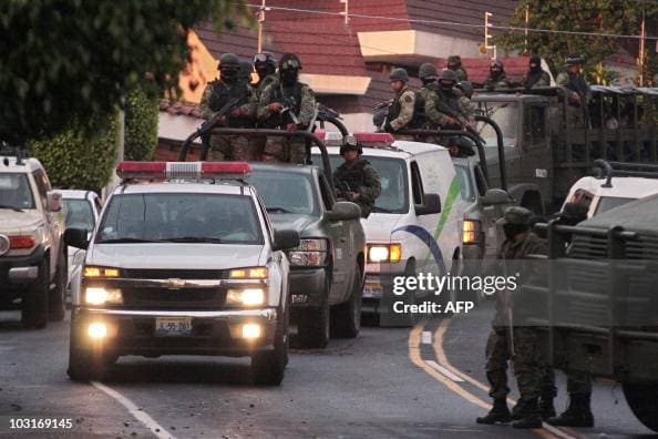 <em>Convoy militar protege el vehículo del Servicio Médico Forense que presuntamente trasladaba los restos de Ignacio "Nacho" Coronel, en Guadalajara, el 30 de julio de 2010. El dirigente del Cártel de Sinaloa murió durante un operativo del Ejército cuando intentaba escapar. (Javier Hoyos/AFP vía Getty Images)</em>