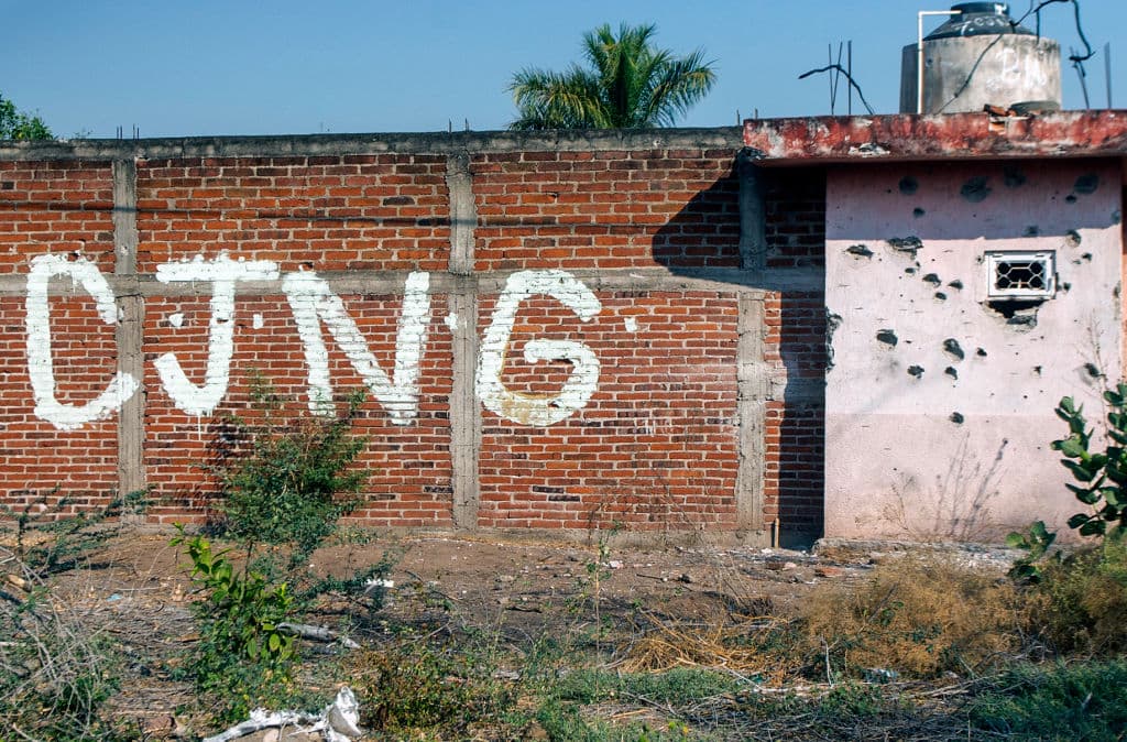 <em>Un muro acribillado a balazos con las iniciales del grupo Cártel Jalisco Nueva Generación (CJNG) a la entrada de la comunidad de Aguililla, en Michoacán, México, el 23 de abril de 2021. (ENRIQUE CASTRO/AFP vía Getty Images)</em>