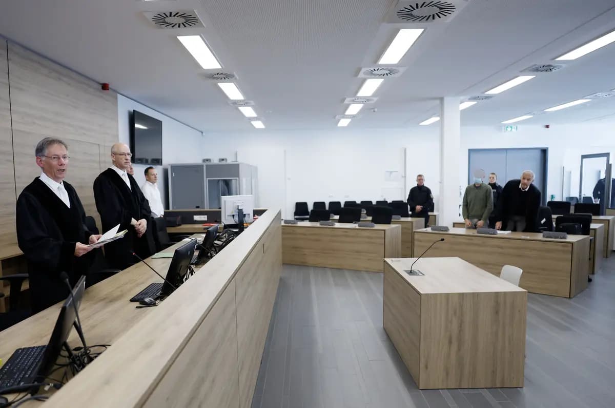 <em>El juez Hans Schlueter-Staats (izquierda) permanece en la sala del tribunal regional superior de Dresde, en el este de Alemania, durante el último día del mediático juicio por espionaje contra dos presuntos espías de China: Jian G. (segundo por la derecha), ex asistente del entonces miembro del Parlamento Europeo Maximilian Krah, del partido de derecha Alternativa para Alemania (AfD), y Yaqi X. (no visible), acusados ​​de espiar a empresas de defensa alemanas, el 30 de septiembre de 2025. (Odd Andersen/POOL/AFP vía Getty Images).</em>