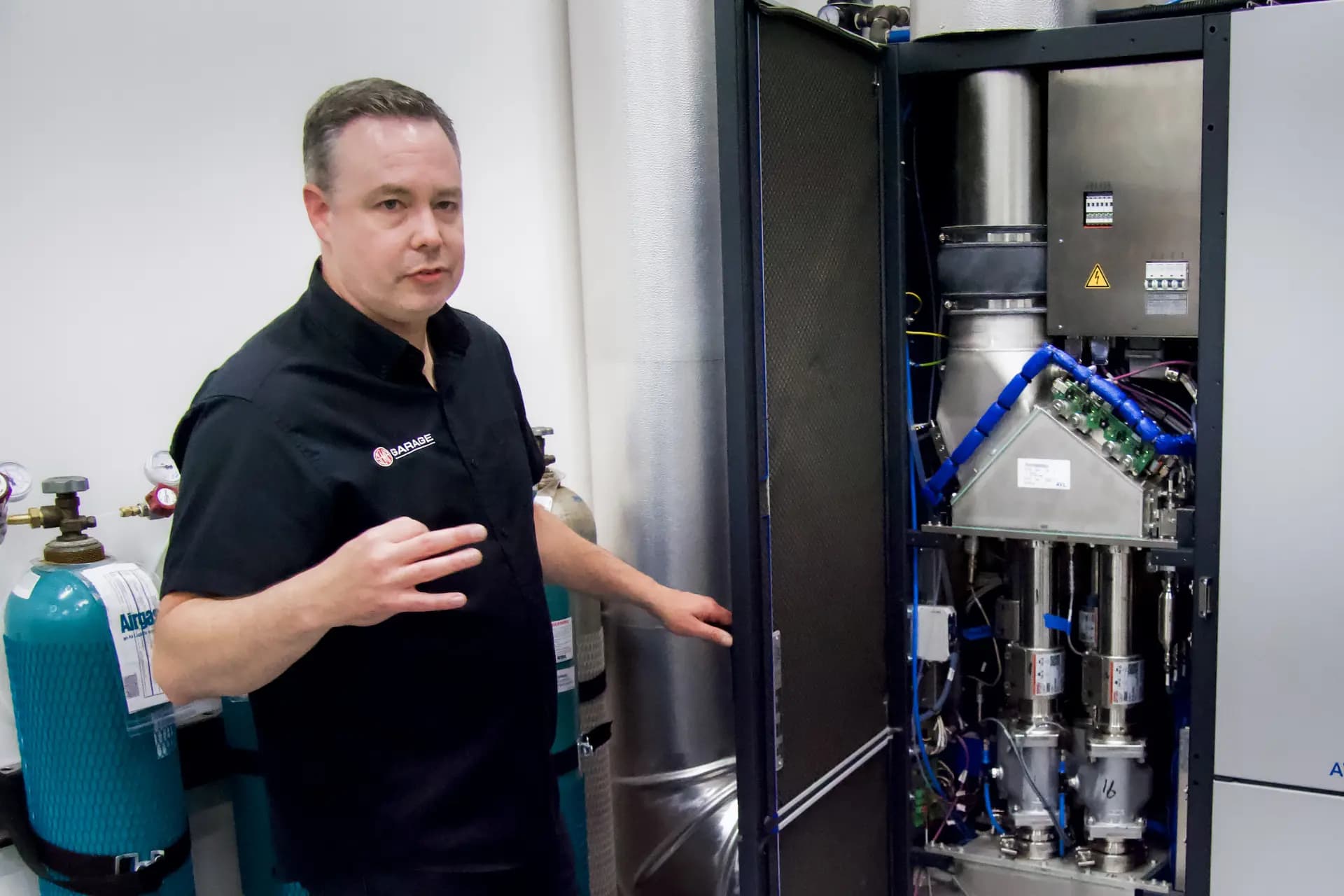 <em>Ben Kaminsky, gerente general del Detroit Garage de SEMA, muestra la tecnología avanzada de control de emisiones utilizada en las instalaciones de prueba en Plymouth, Michigan, el 28 de julio de 2026. (Travis Gillmore/The Epoch Times).</em>