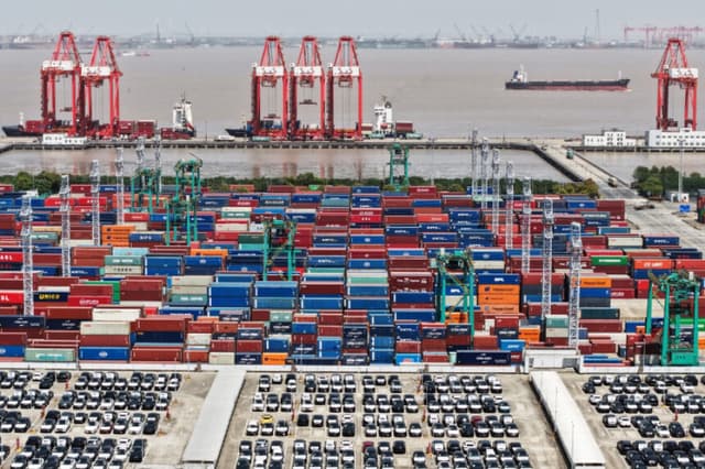 Una imagen tomada con un dron muestra vehículos eléctricos (VE) destinados a la exportación y contenedores en un puerto de Shanghái, China, el 13 de abril de 2025. (China Daily vía Reuters).