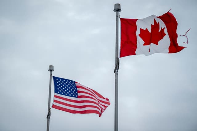 Las banderas de Canadá y Estados Unidos ondean cerca de la frontera entre ambos países en Blackpool, Quebec, Canadá, el 2 de febrero de 2025. (ANDREJ IVANOV/AFP vía Getty Images)
