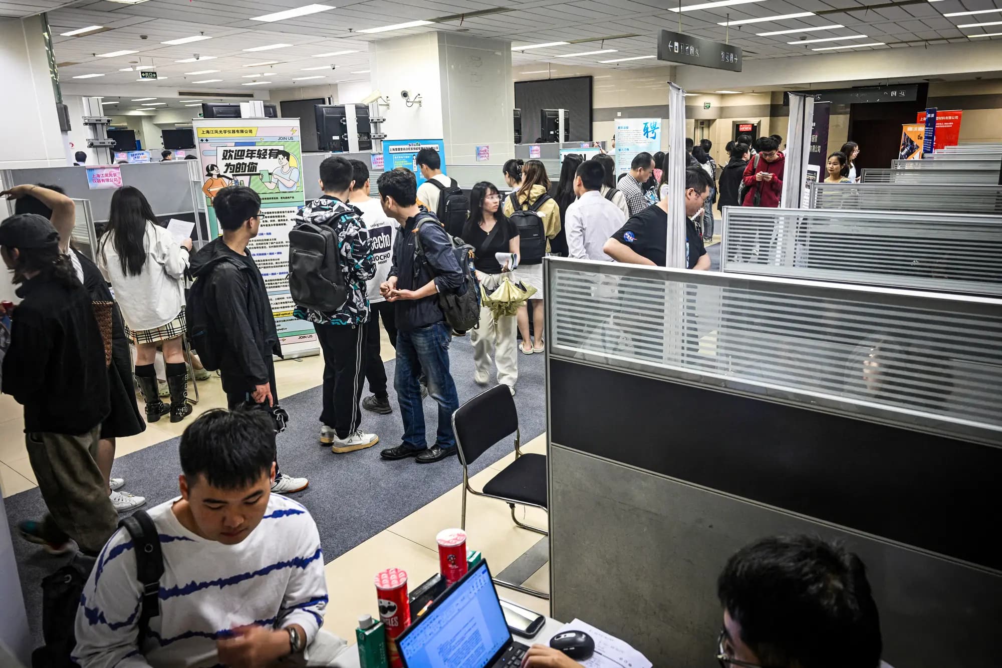 <em>Varias personas visitan una feria de empleo en el distrito de Jing'an, Shanghái, el 5 de junio de 2024. Debido a los recortes de costos de muchas multinacionales, quienes buscan empleo en China se encuentran bajo presión. (Hector Retamal/AFP vía Getty Images).</em>