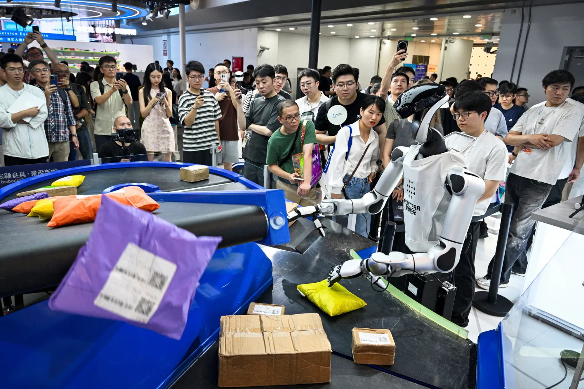 <em>Un robot humanoide de Robotera manipula paquetes durante la Conferencia Mundial de Inteligencia Artificial en Shanghái, el 18 de julio de 2026. China está invirtiendo fuertemente en IA a pesar de la disminución general de la inversión. (Hector Retamal/AFP vía Getty Images).</em>