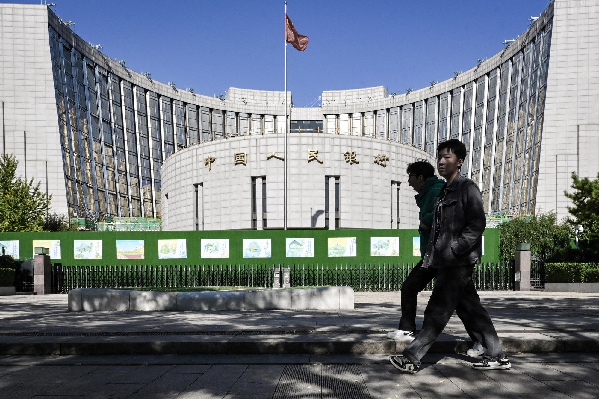 <em>Varias personas pasan frente al Banco Popular de China, el banco central del país, en Beijing, el 19 de octubre de 2024. (Adek Berry/ AFP vía Getty Images).</em>