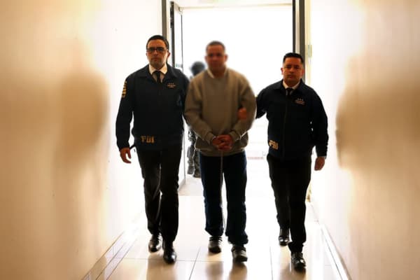 Fotografía cedida por la Policía de Investigaciones de Chile (PDI) que muestra a Alfredo Carrillo Ortiz (c), conocido como el "Gocho", siendo trasladado por funcionarios de PDI este viernes, en la base Grupo 10 de la Fuerza Aérea de Chile, en Santiago (Chile). (EFE/ Policía de Investigaciones de Chile)