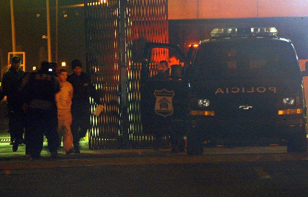 <em>Policías de la Agencia Federal de Investigación (AFI) custodian a Iván Archivaldo Guzmán, el Chapito, en el penal de La Palma, Estado de México, el 9 de junio de 2005, antes de su traslado (Hernán Vázquez / Agencia MVT / AFP vía Getty Images)</em>