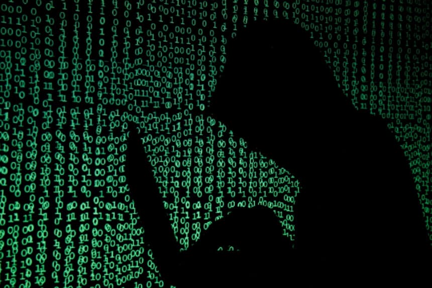 En esta ilustración, un hombre encapuchado sostiene una computadora portátil mientras se proyecta código cibernético sobre ella. (Kacper Pempel/Reuters).