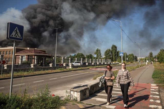 Los residentes pasan junto al lugar donde un dron ruso lanzó un ataque mientras se eleva el humo, en medio de la invasión de Rusia a Ucrania, en la región de Kiev, Ucrania, el 29 de agosto de 2026. (Alina Smutko/Reuters)