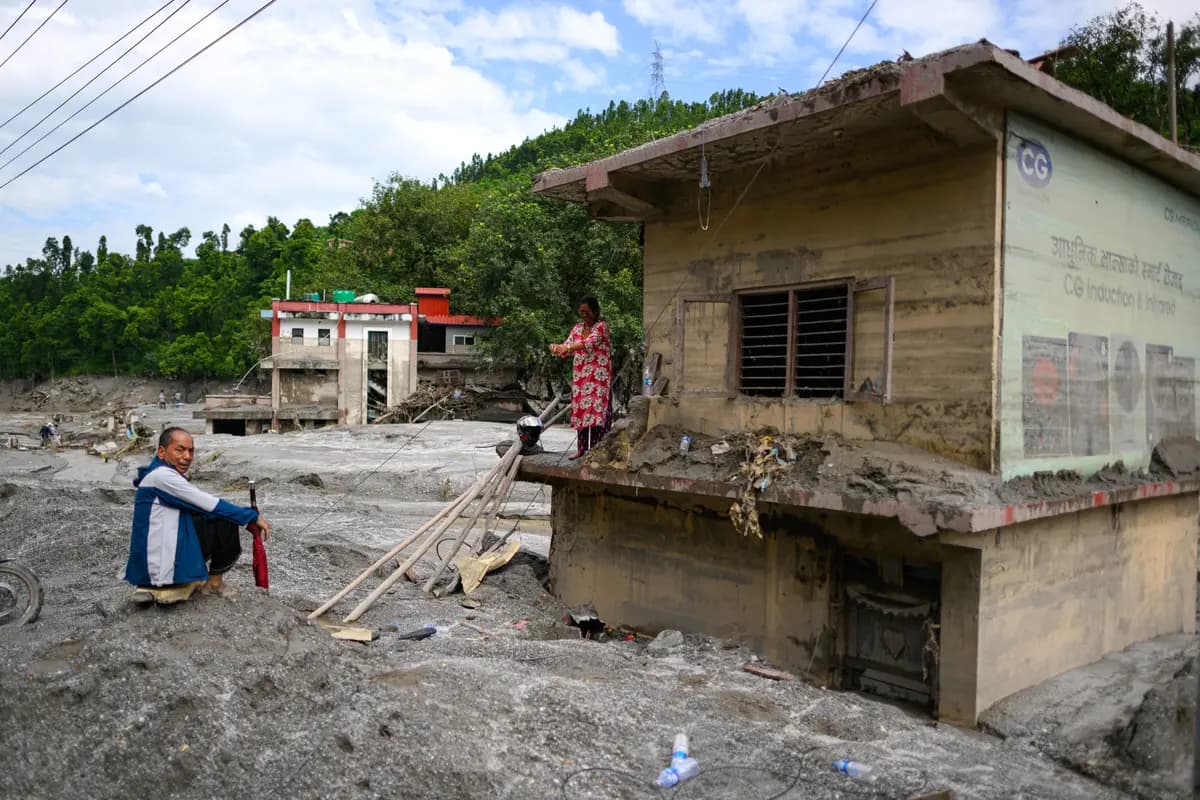 Una mujer (derecha) se encuentra de pie sobre el techo de su casa cubierta de lodo tras las inundaciones repentinas en Baireni, en el distrito de Dhading, Nepal, el 30 de agosto de 2026. (Manan Vatsyayana/AFP vía Getty Images).