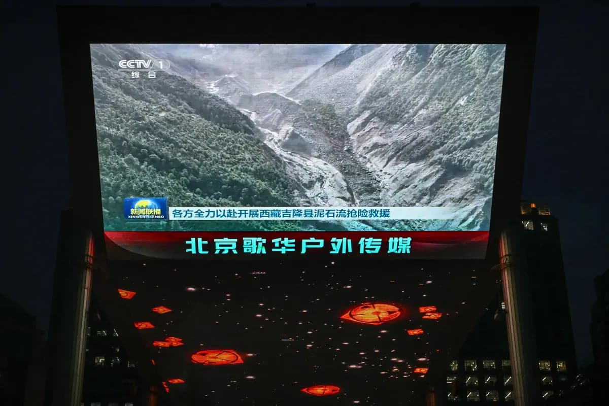 Una pantalla gigante en el exterior de un centro comercial en Beijing muestra un reportaje con imágenes de un deslizamiento de tierra en el condado de Gyirong, en la región del Tíbet occidental chino, cerca de la frontera con Nepal, el 27 de agosto de 2026. (Greg Baker/AFP vía Getty Images).