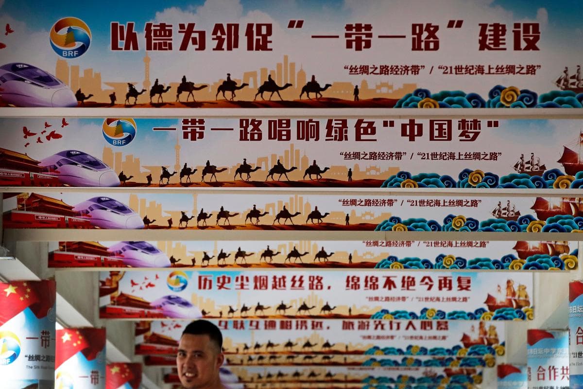 Un hombre se encuentra bajo las columnas que exhiben el emblemático plan de política exterior del líder chino Xi Jinping, "El Sueño Chino" y "La Franja, la Ruta", durante un evento en Beijing el 29 de junio de 2018. (Andy Wong/AP)