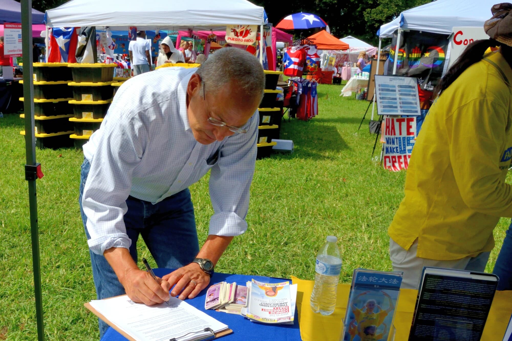 El candidato al Senado Mike Katz firma una petición contra la extracción de órganos en China durante un festival en Delaware. (Frank Liang/The Epoch Times).