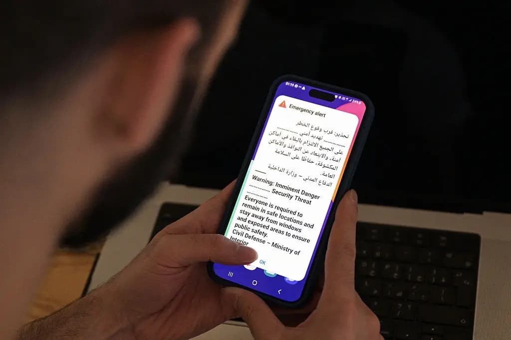 Un hombre kuwaití sostiene su teléfono celular, en el que se muestra un mensaje de alerta, mientras suenan las sirenas durante un ataque iraní con misiles o drones, en la ciudad de Kuwait en la madrugada del 2 de septiembre de 2026. (Foto de AFP vía Getty Images)