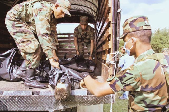 Soldados del ejército colombiano descargan los cuerpos de guerrilleros de las Fuerzas Armadas Revolucionarias de Colombia (FARC) y del Ejército de Liberación Nacional (ELN) el 20 de marzo de 2003, en Río Negro, cerca de Medellín. Imagen de Archivo (FREDY AMARILES/AFP vía Getty Images)