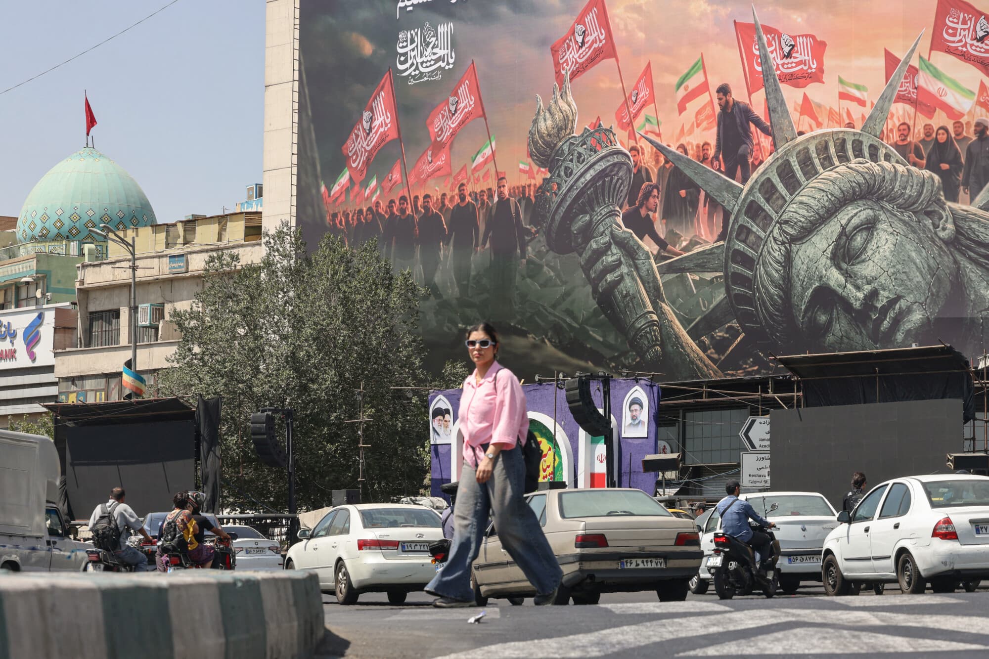 La gente pasa junto a una valla publicitaria contra Estados Unidos en la plaza Enghelab, en el centro de Teherán, el 2 de septiembre de 2026. Las fuerzas iraníes anunciaron el 2 de septiembre que lanzaron ataques contra objetivos militares estadounidenses en los Emiratos Árabes Unidos, Kuwait, Baréin y otros países de la región, y advirtieron que habría consecuencias «graves» si Estados Unidos volvía a atacar a la República Islámica. (Atta KENARE / AFP vía Getty Images)