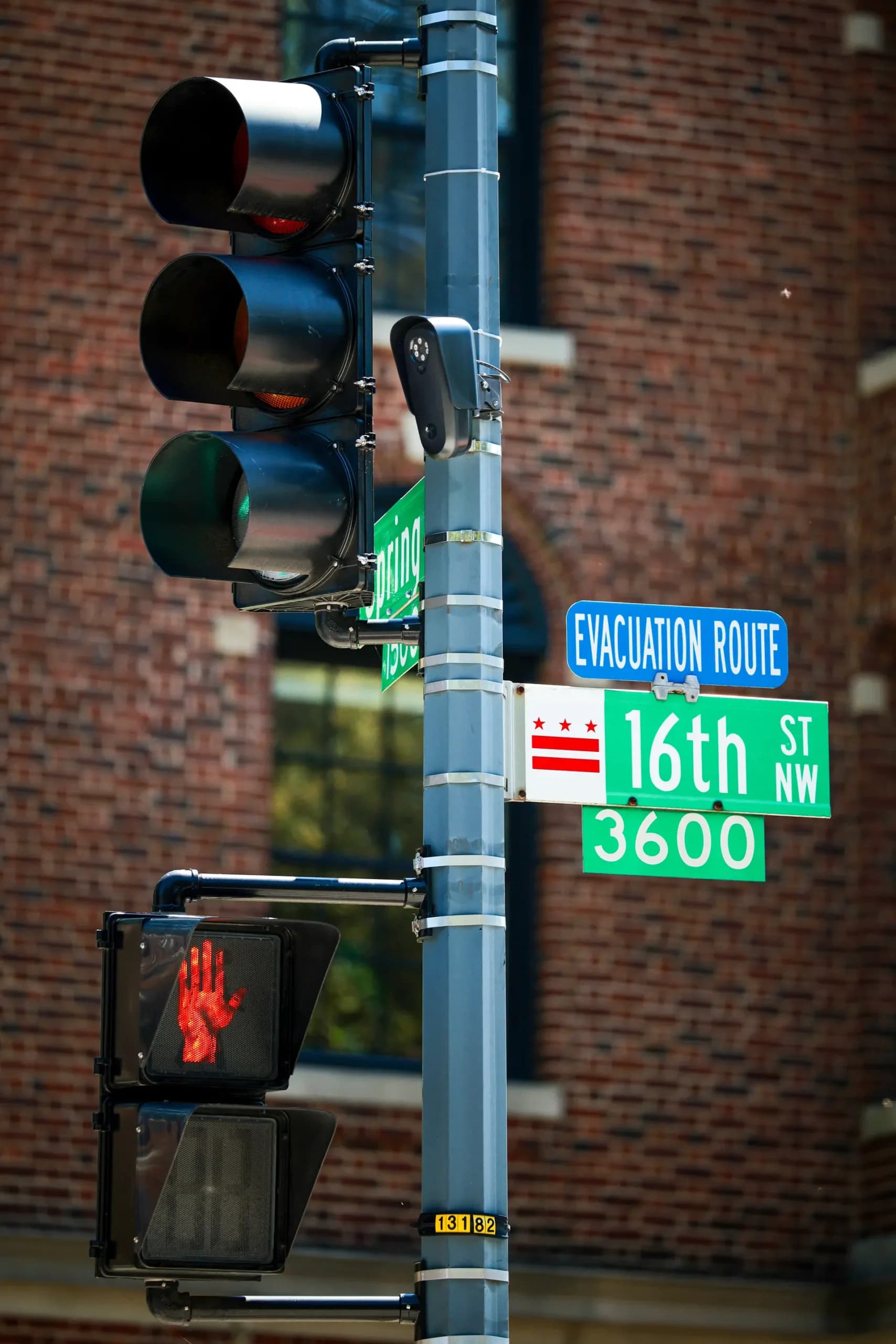 (Izquierda) Una cámara lectora automática de matrículas de Flock Safety está instalada en un poste de semáforo en la calle 16 Noroeste de Washington el 19 de agosto de 2026. (Derecha) Un letrero pegado a una farola señala una cámara lectora automática de matrículas de la marca Flock en la calle 16 Noroeste de Washington el 19 de agosto de 2026. (Chip Somodevilla/Getty Images).