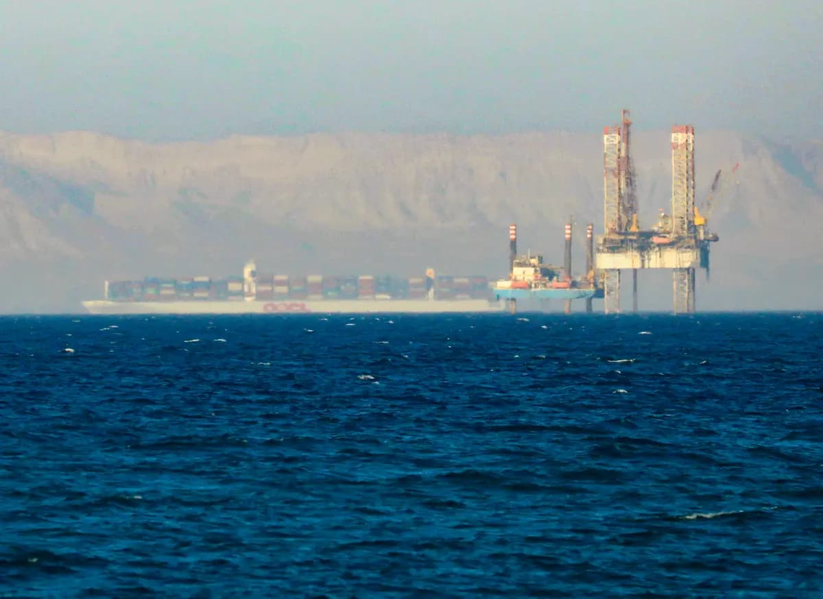 <em>Un buque portacontenedores cruza una plataforma petrolífera en el Golfo de Suez en dirección al Mar Rojo antes de entrar en el Canal de Suez, en las afueras de El Cairo, Egipto, el 1 de septiembre de 2020. (Amr Abdallah Dalsh/Reuters).</em>