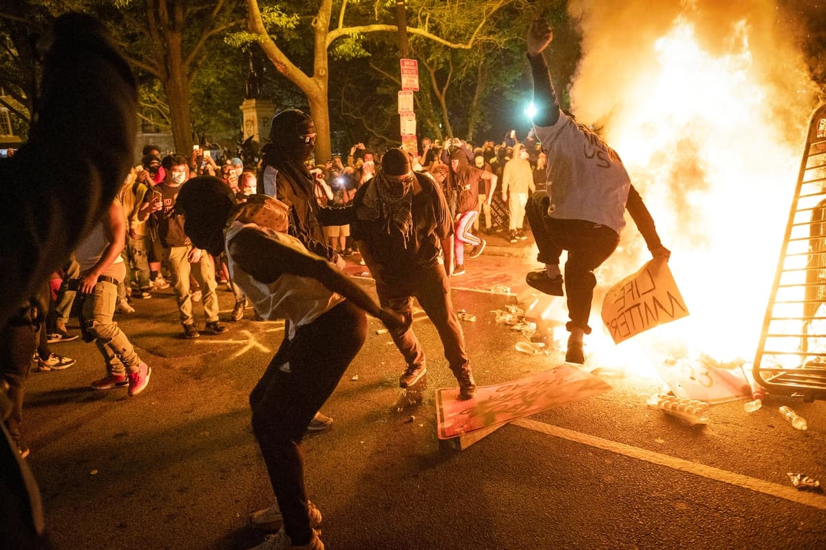 Manifestantes saltan sobre un letrero de calle cerca de una barricada en llamas durante un disturbio por la muerte de George Floyd, cerca de la Casa Blanca, el 31 de mayo de 2020. La conciencia pública sobre Antifa se disparó ese verano cuando algunos de sus miembros se unieron a las manifestaciones de Black Lives Matter. (Robert Schmidt/AFP vía Getty Images)