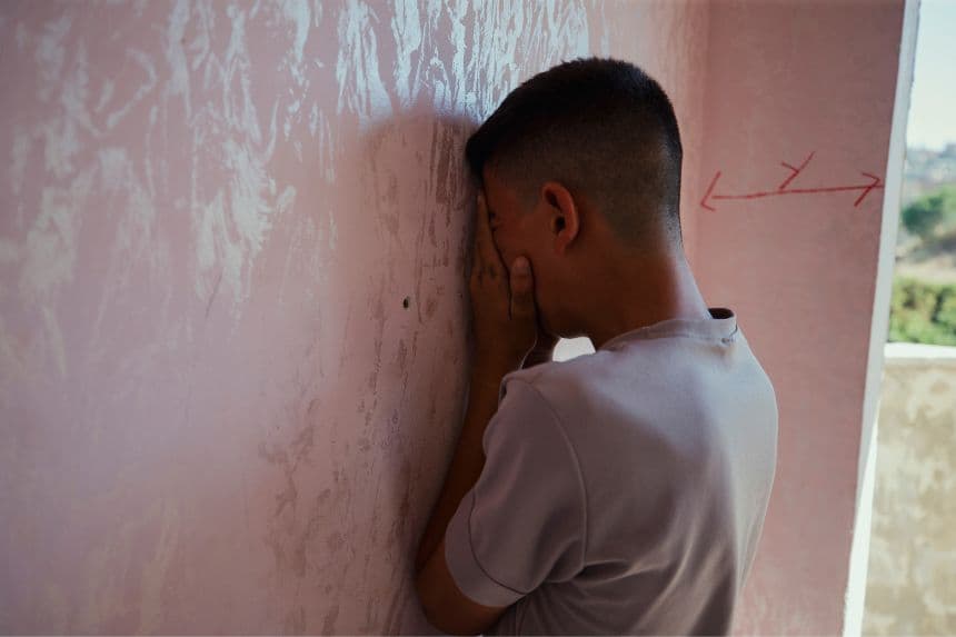 Un niño llora recostado contra la pared en una habitación. (WAHAJ BANI MOUFLEH/Middle East Images/AFP vía Getty Images)
