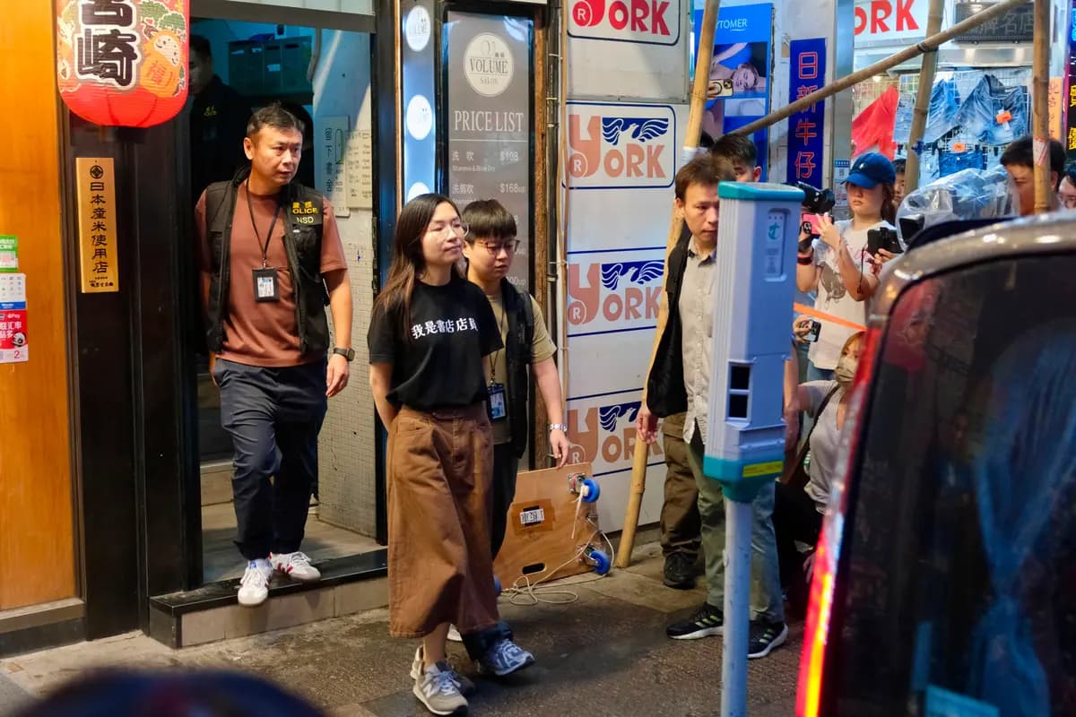 Un empleado de una librería independiente es escoltado por agentes de policía después de que estos realizaran una redada en la librería "Have A Nice Stay" y confiscaran artículos en Hong Kong el 15 de julio de 2026. (Tommy Wang/AFP vía Getty Images)