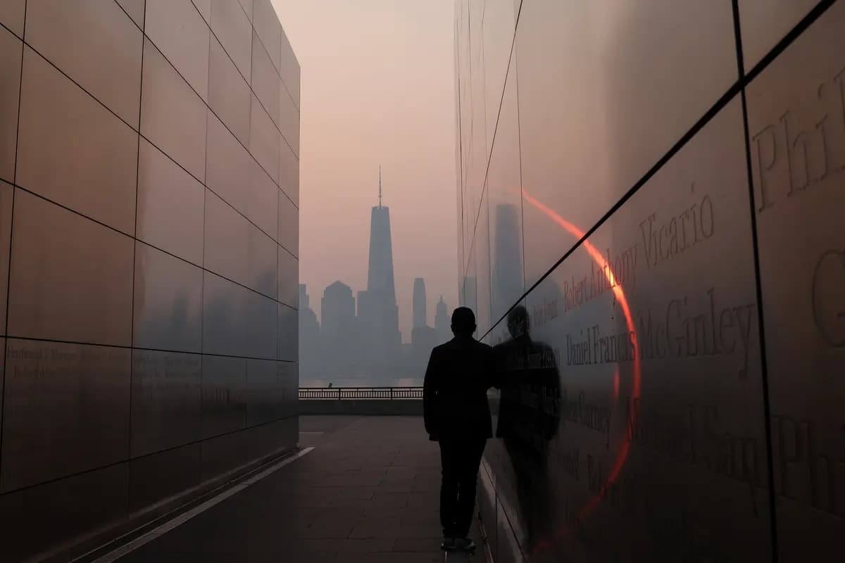 Un hombre se encuentra en el monumento conmemorativo "Empty Sky 911" en Jersey City, Nueva Jersey, mirando hacia la torre del One World Trade Center en el sur de Manhattan, en la ciudad de Nueva York, poco después del amanecer, mientras la neblina y el humo de los incendios forestales en Canadá se ciernen sobre el horizonte de Manhattan, el 8 de junio de 2023. (Mike Segar/Reuters)