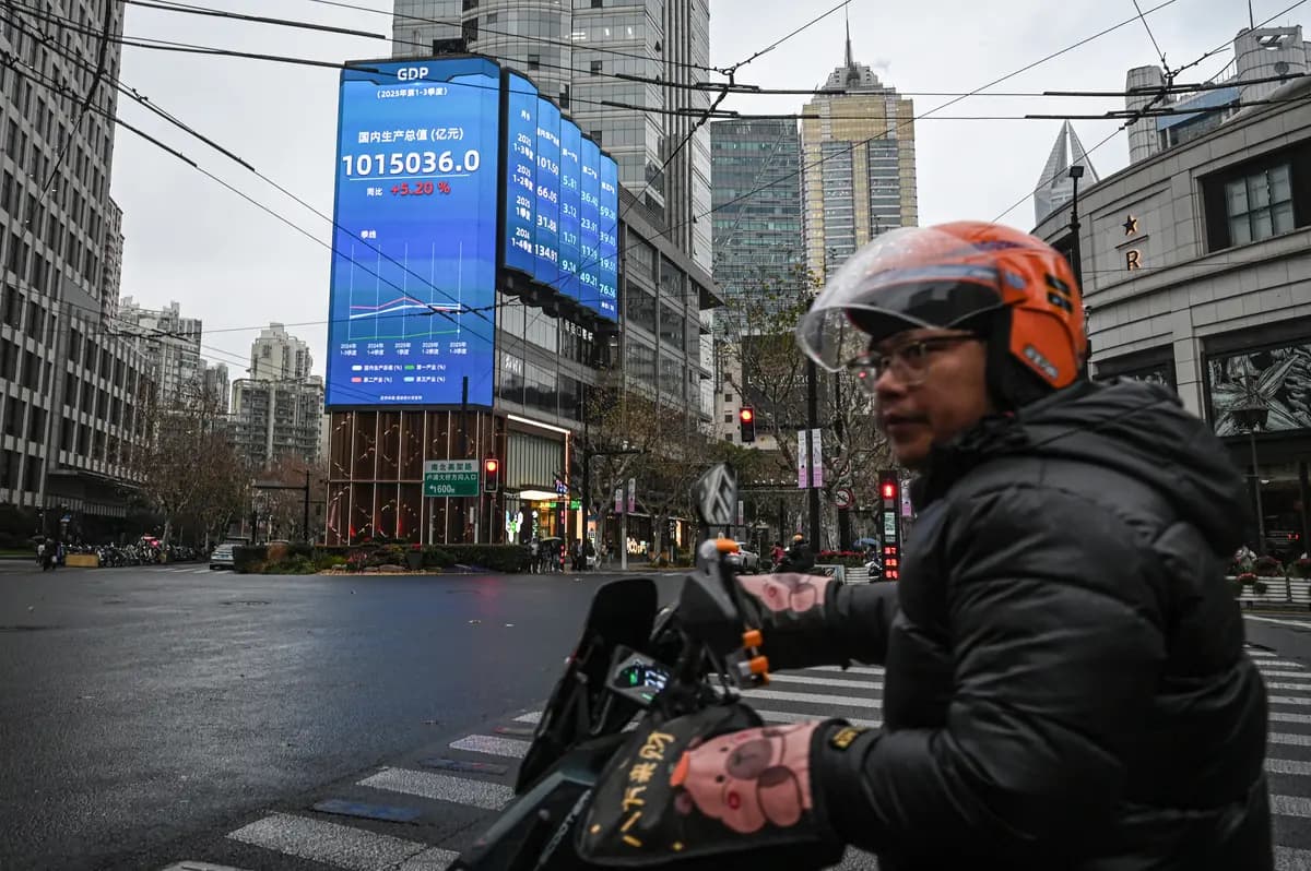 <em>Un hombre pasa en scooter frente a una pantalla que muestra cifras del producto interno bruto (PIB) en una calle de Shanghái el 19 de enero de 2026. (Jade Gao/AFP vía Getty Images).</em>