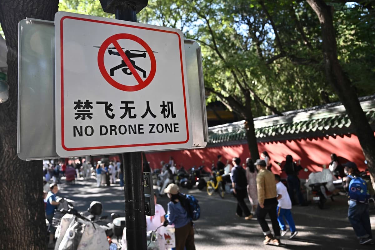 Varias personas pasan junto a un cartel que dice "Zona prohibida para drones" en un callejón de Beijing el 14 de septiembre de 2026. (Pedro Pardo/AFP vía Getty Images).