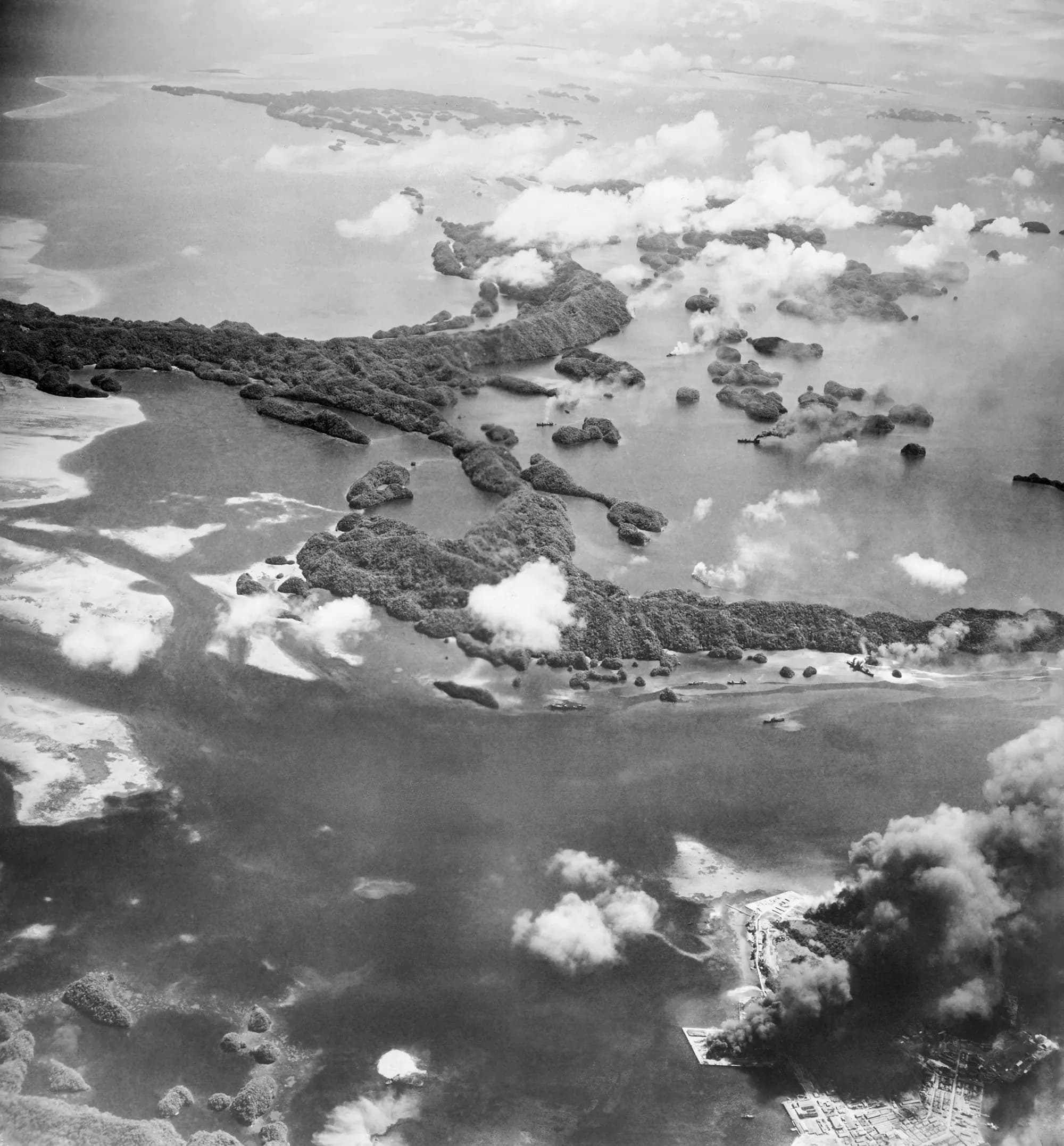 <em>Columnas de humo se elevan desde los muelles y edificios de Palaos el 29 de junio de 1944, mientras bombarderos de la Armada estadounidense atacan una base japonesa. Sucesivas potencias coloniales —España, Alemania y Japón— gobernaron Palaos antes de que el archipiélago quedara bajo administración estadounidense como territorio en fideicomiso de las Naciones Unidas en 1947. (Foto AP).</em>