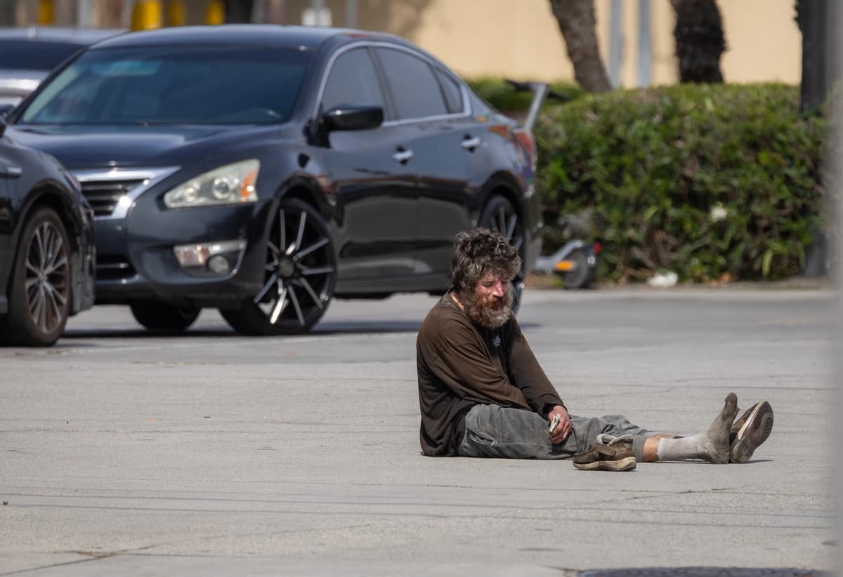 Un hombre sin hogar sostiene dinero en efectivo en Los Ángeles el 13 de agosto de 2026. (John Fredricks/The Epoch Times)
