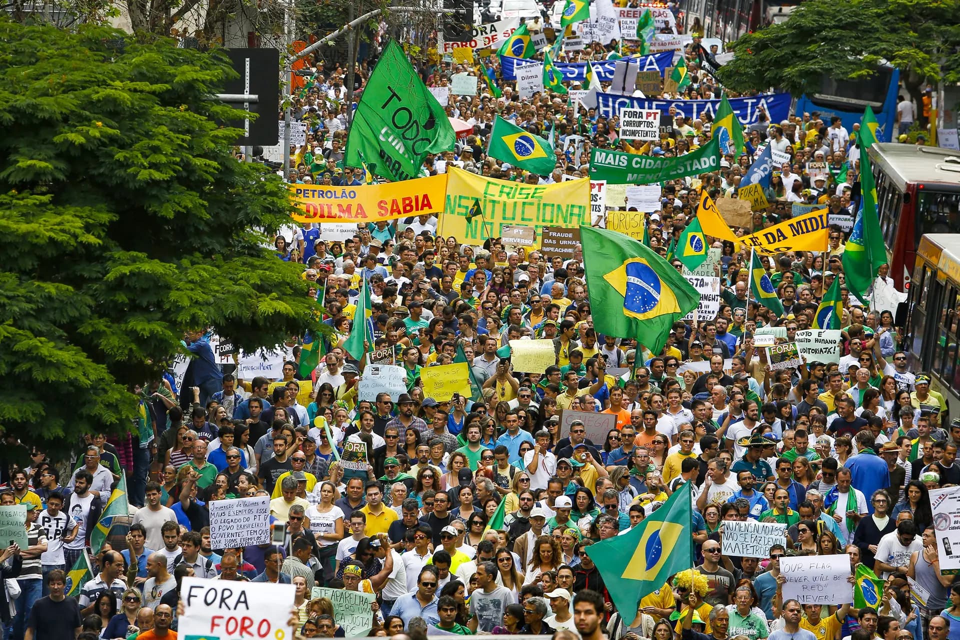 Los manifestantes sostienen pancartas con los mensajes "Crisis institucional en Brasil" y "Dilma lo sabía" mientras participan en una protesta para exigir la destitución de la presidenta Dilma Rousseff, en São Paulo, el 15 de noviembre de 2014. El candidato presidencial brasileño Renan Santos fue una figura destacada en las manifestaciones contra Rousseff. (Miguel Schincariol/AFP vía Getty Images).
