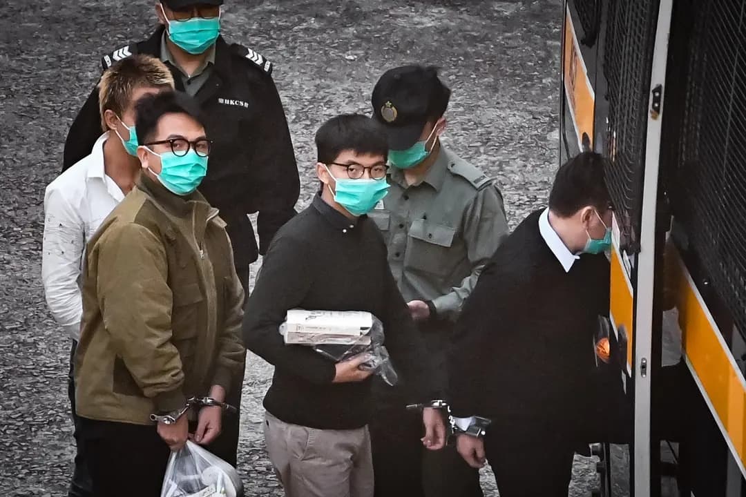 Los activistas Joshua Wong (C) e Ivan Lam (D) suben a una camioneta policial antes de ser trasladados a la corte para recibir su sentencia por una protesta de 2019 que tuvo lugar frente a la sede de la policía de la ciudad, en un centro penitenciario de máxima seguridad en Hong Kong el 2 de diciembre de 2020. (Anthony Wallace/AFP vía Getty Images)