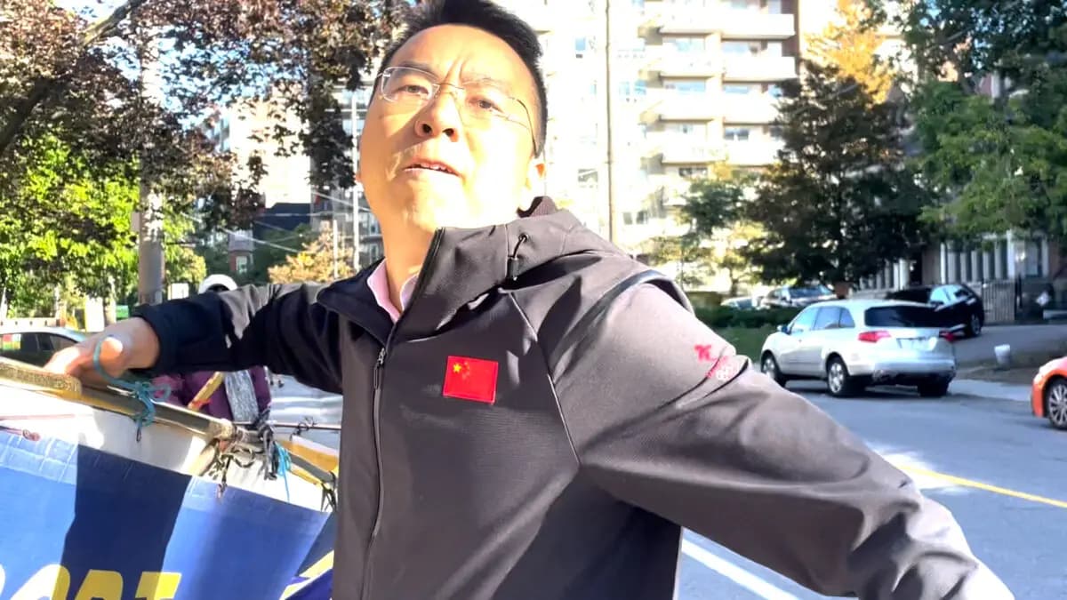 <em>Un hombre ataca a una practicante de Falun Gong que lo filma mientras retira a la fuerza sus pancartas en una acera pública frente al Consulado Chino en Toronto, el 22 de septiembre de 2026. (Captura de pantalla/Imagen cedida).</em>