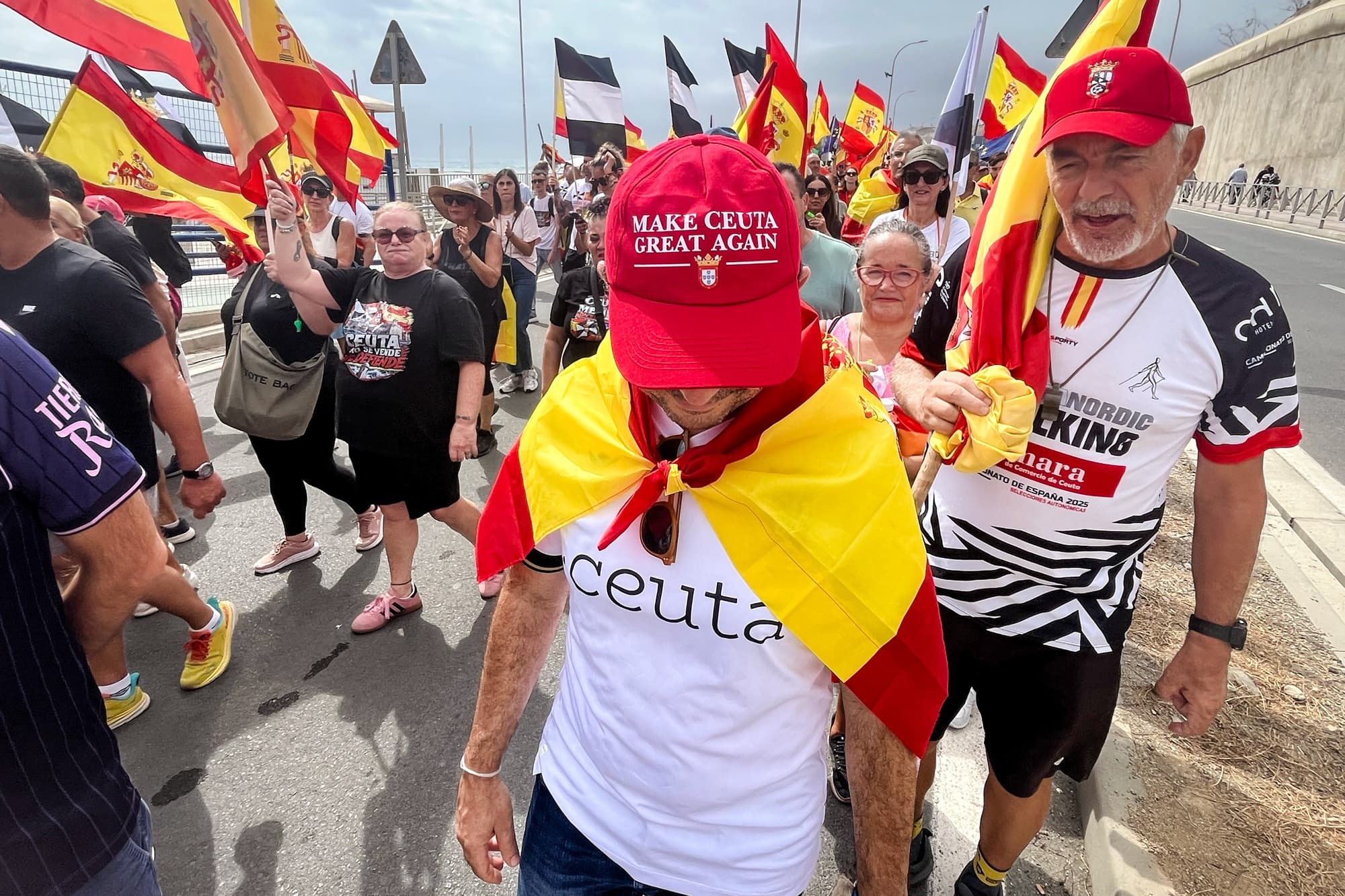 Un manifestante lleva una bandera de España a modo de capa y una gorra con el lema «Make Ceuta Great Again» durante una marcha hacia la frontera del Tarajal, en Ceuta, España, el 20 de septiembre de 2026. (Etienne Fauchaire/The Epoch Times).