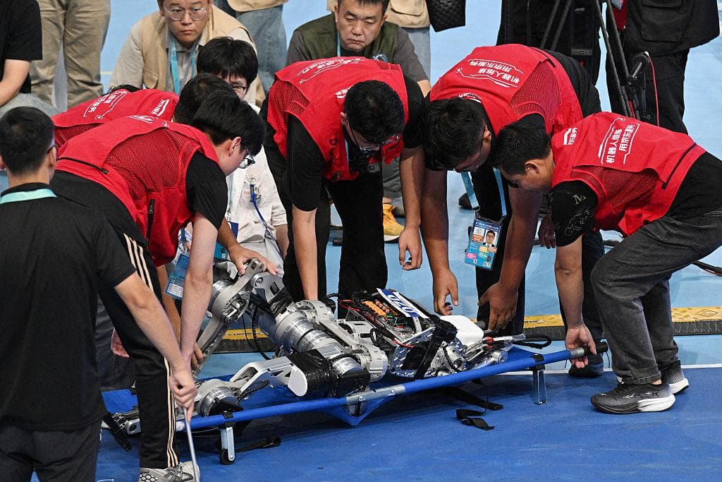 <em>Un robot humanoide es evacuado tras caer durante la competición de salto de longitud en los II Juegos Mundiales de Robots Humanoides, celebrados en el Óvalo Nacional de Patinaje de Velocidad de Beijing el 26 de agosto de 2026. (Greg Baker/AFP vía Getty Images).</em>
