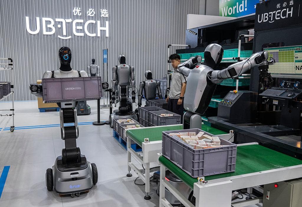 <em>Un técnico supervisa a robots humanoides de la empresa china UBTECH mientras demuestran sus habilidades laborales en un entorno que simula un almacén industrial, durante la Conferencia Mundial de Robótica celebrada en Beijing, China, el 20 de agosto de 2026. (Kevin Frayer/Getty Images).</em>