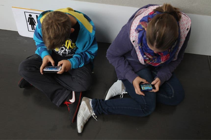  Unos niños juegan a videojuegos en sus teléfonos inteligentes mientras asisten a un acto público el 22 de septiembre de 2012.  (Sean Gallup/Getty Images)