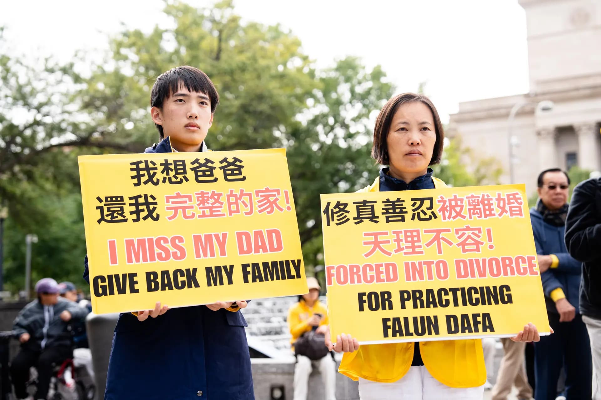 Fei Feng Lou, cuyo esposo fue obligado a divorciarse de ella en China, y su hijo Runxin Wang sostienen pancartas en una manifestación organizada por practicantes de Falun Gong para exigir el fin de la persecución del Partido Comunista Chino contra esta práctica espiritual, durante la visita de Estado del líder chino Xi Jinping a Washington el 24 de septiembre de 2026. (Samira Bouaou/The Epoch Times)